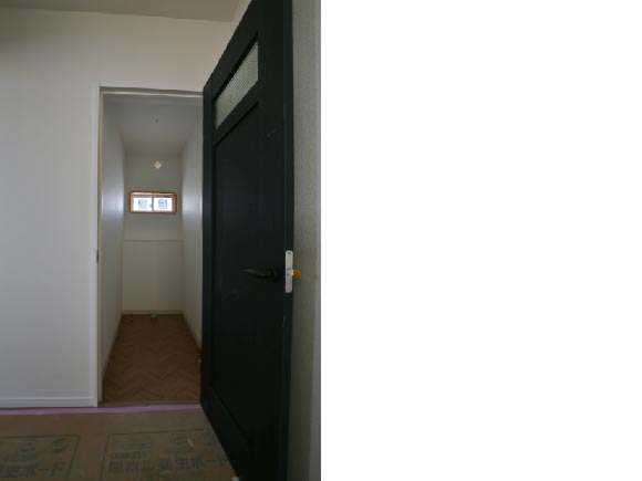 クラフトレーベルのネイビーオーク柄のトイレの扉とヘリンボーン柄のクッションフロア